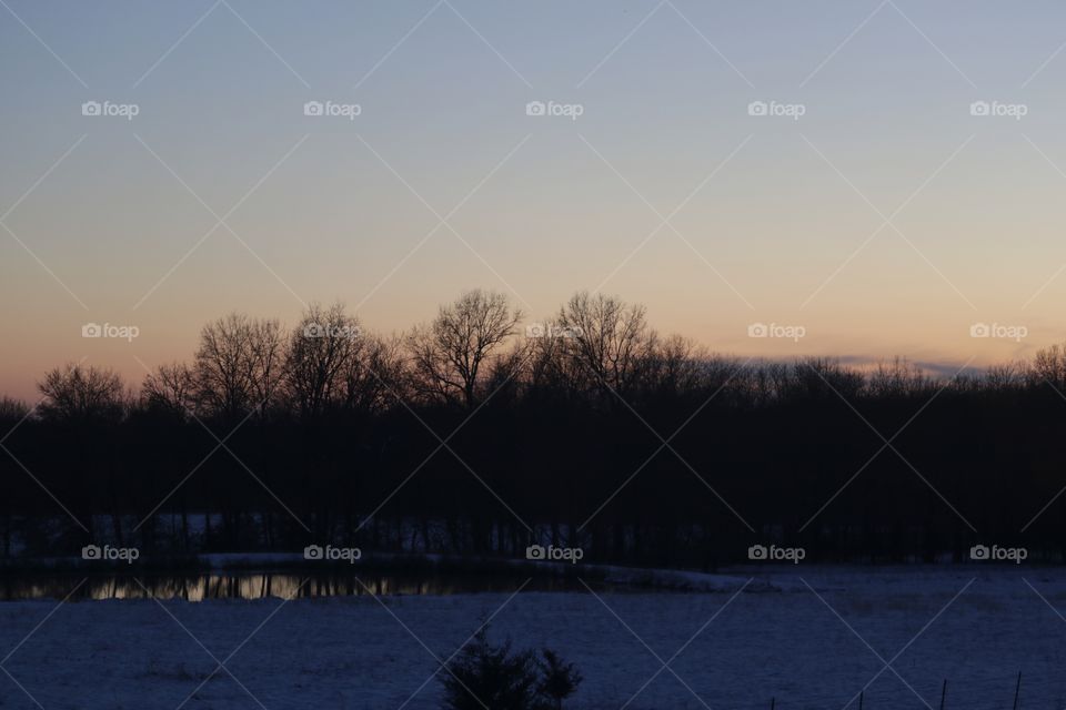 A glowing sunset over the fields covered in snow.