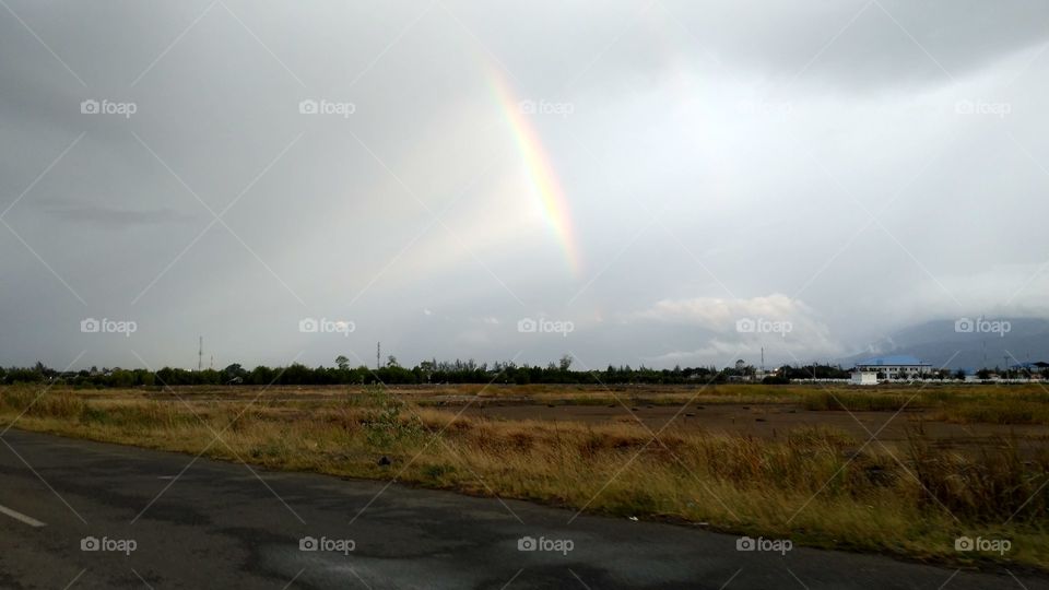 Rainbow view from the road with a field background