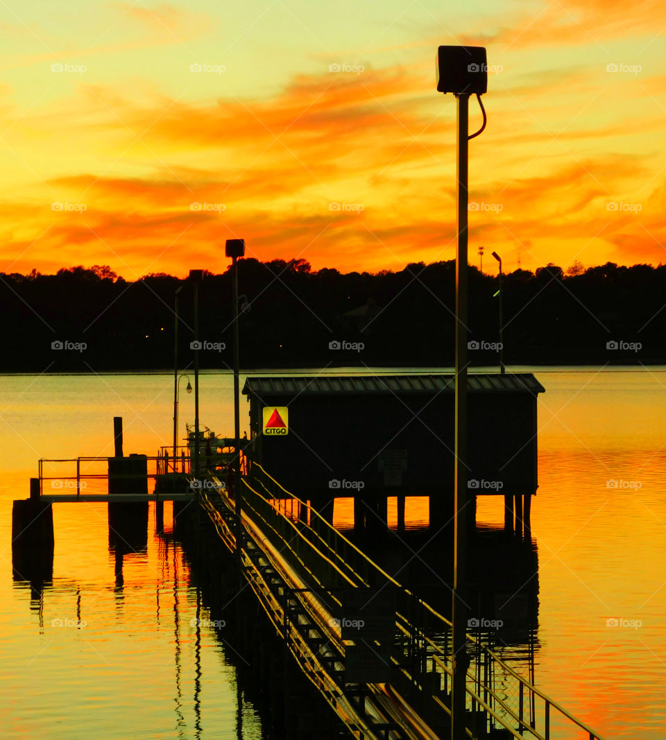 Silhouette of pier in lake at sunset