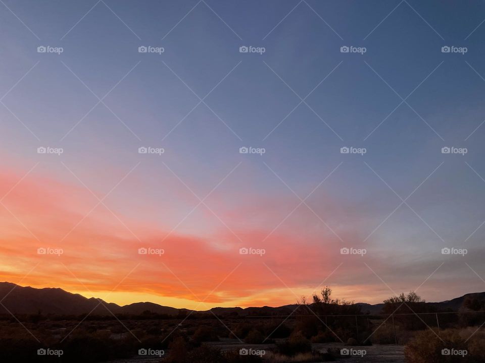 A colorful sunset with mountains and clouds. 