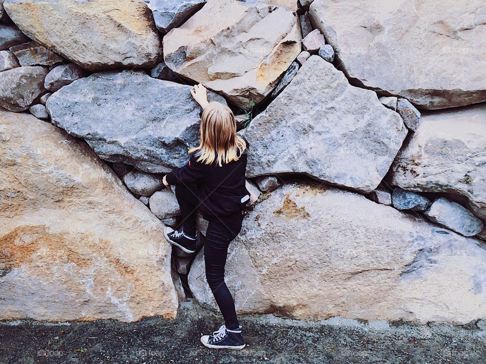 Trying to climb. A girl is trying to climb the stonewall