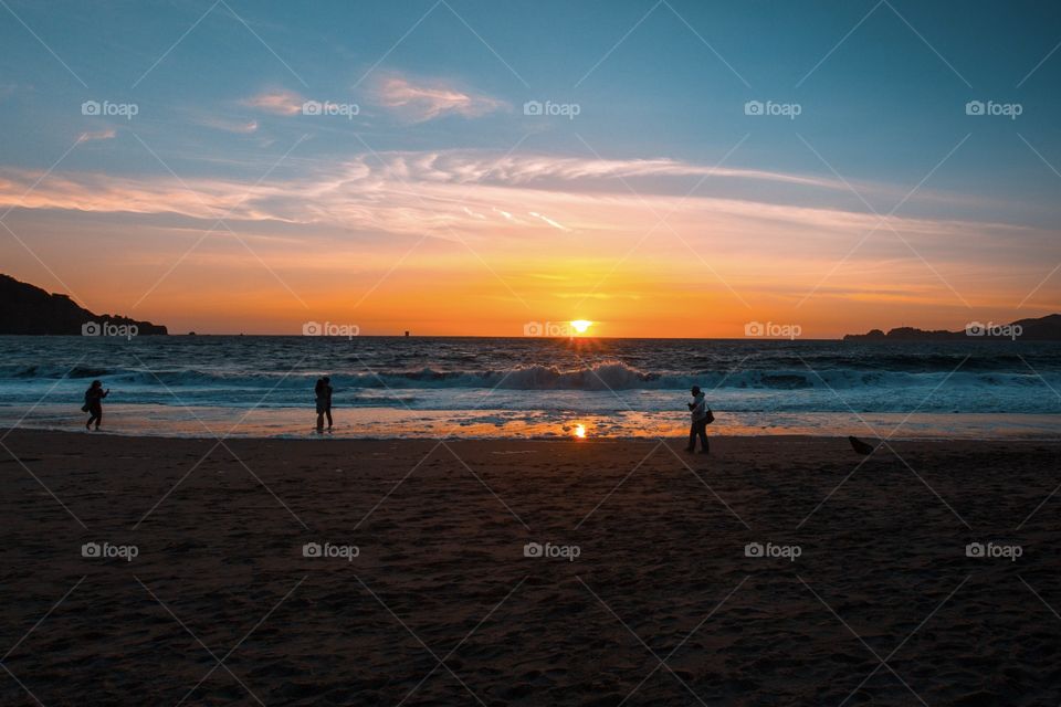 People walking by the beach during golden hour 