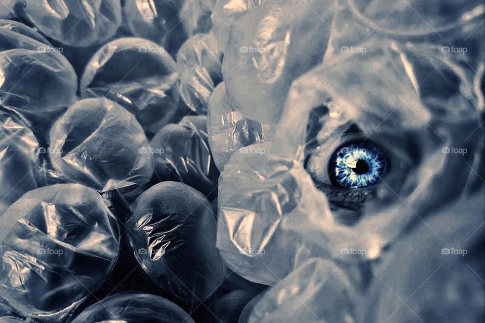 A blue eye looks through blue bubble wrap 