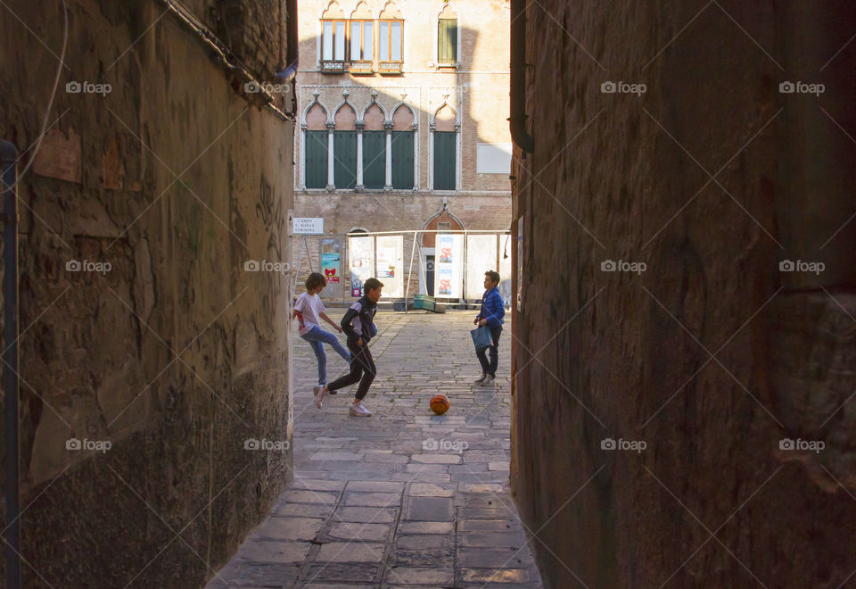 Boys are playing football on a square in Venice in the evening. The masses of tourists left the city. Time to play!