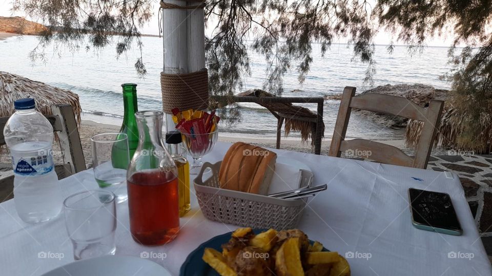 greece. dining tabke. cafetiere wine. bread dinner. ocean view. beach. evening