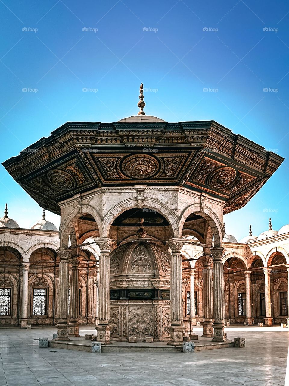 A marble ablution fountain with detailed Ottoman carvings stands in the courtyard of the Mohamed Ali Mosque in Cairo.