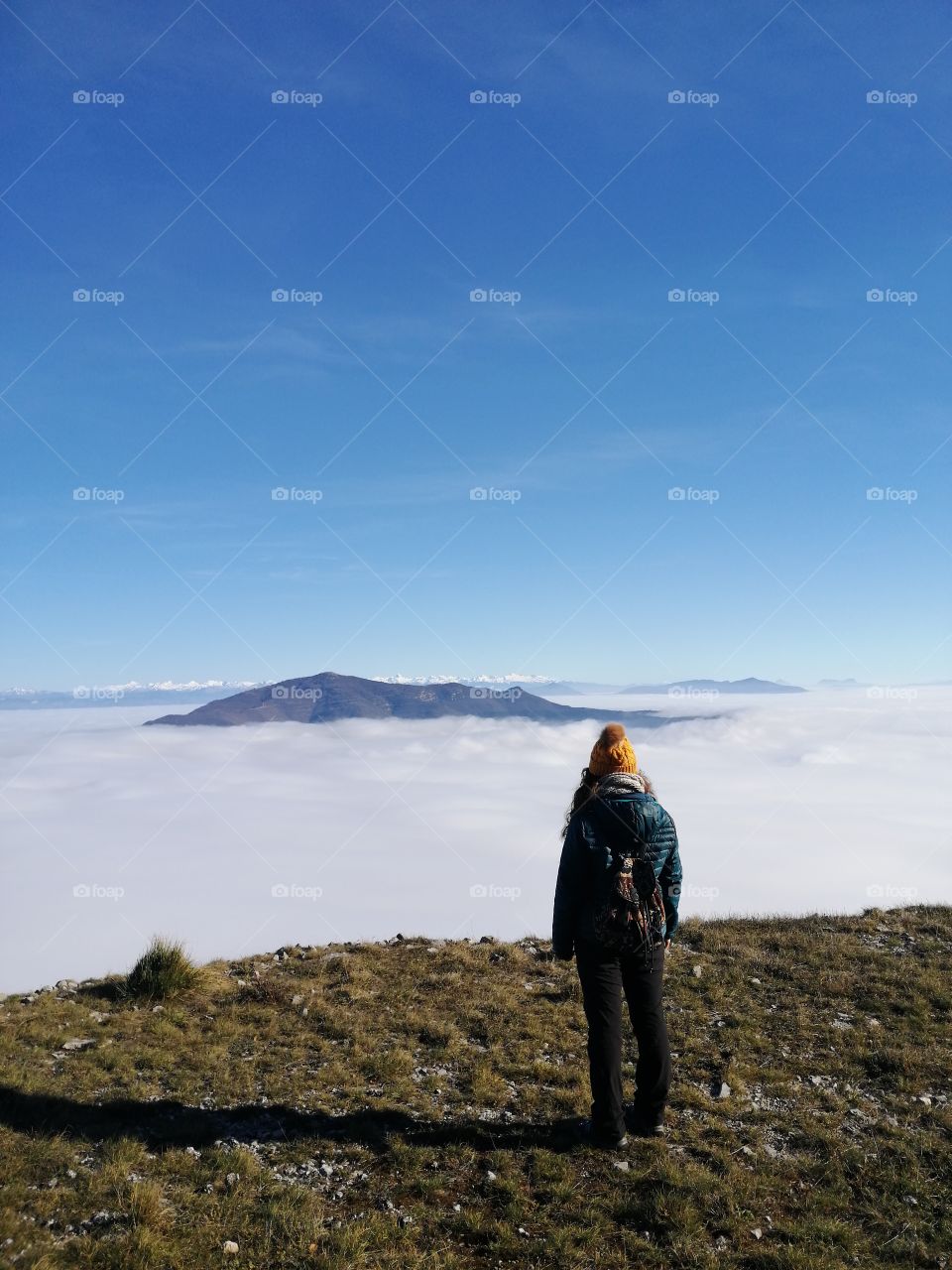 Young girl on the top of a mountain in front of the cloud landscape.