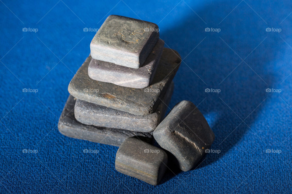 Stack of square and rectangle shaped slate stones on a blue background with interesting light and shadows