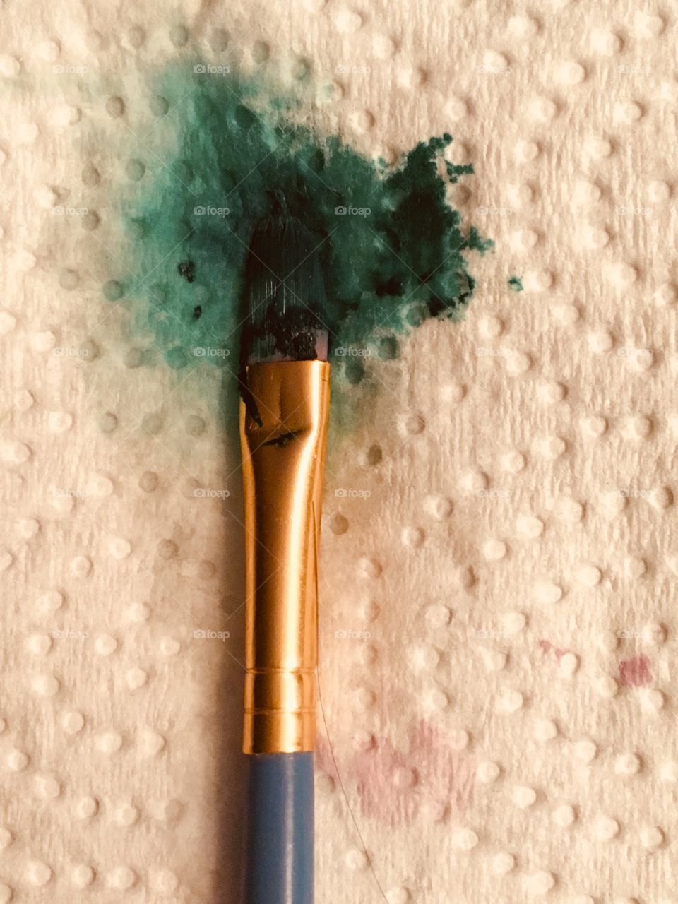 A close up of a used paintbrush resting on a paper towel