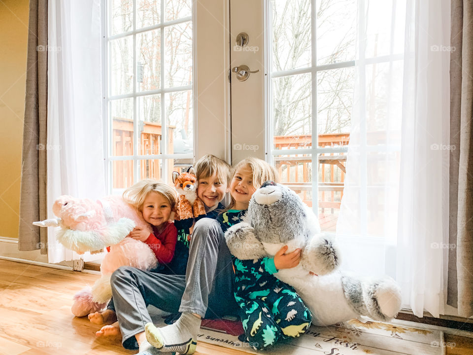 Kids smiling together and holding stuffed animals 