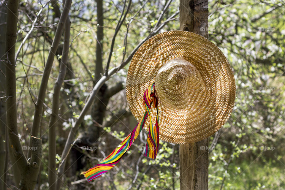 Straw hat hanging on wooden collumn on country house, summertime