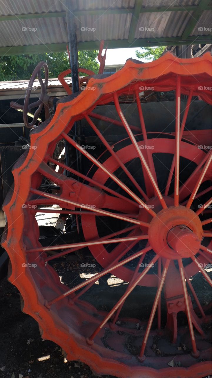 Huge wheels on an antique vehicle painted orange