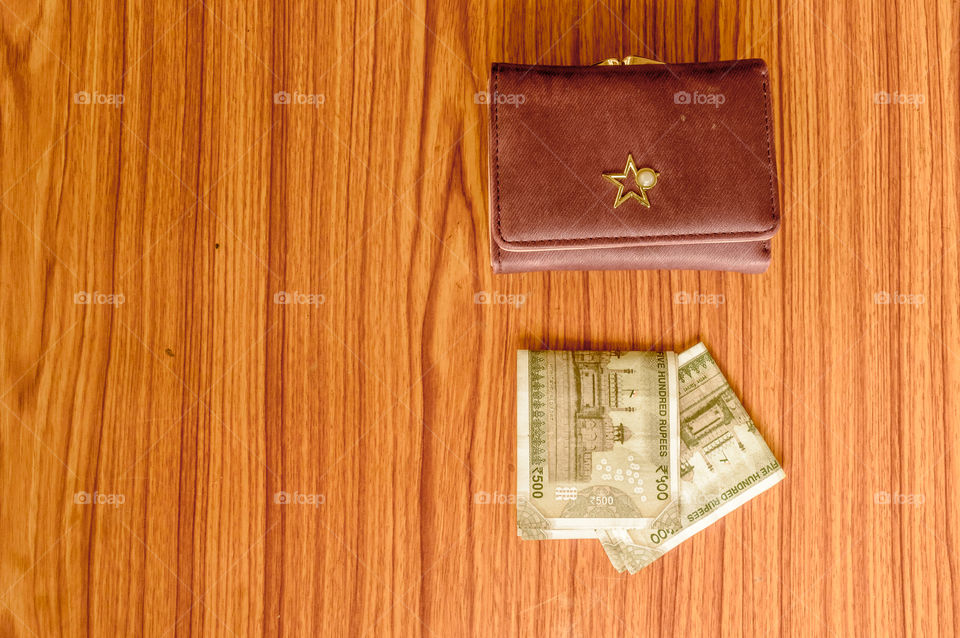 Indian five hundred (500) rupee cash note in brown color wallet leather purse on a wooden table. Business finance economy concept. High angel view with copy space room for text on left side of image