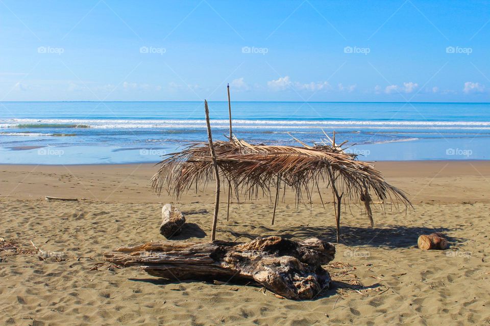 An improvised  parasol mada of palm branches on the empty sandy beach of Paloseco on the Pacific ocean