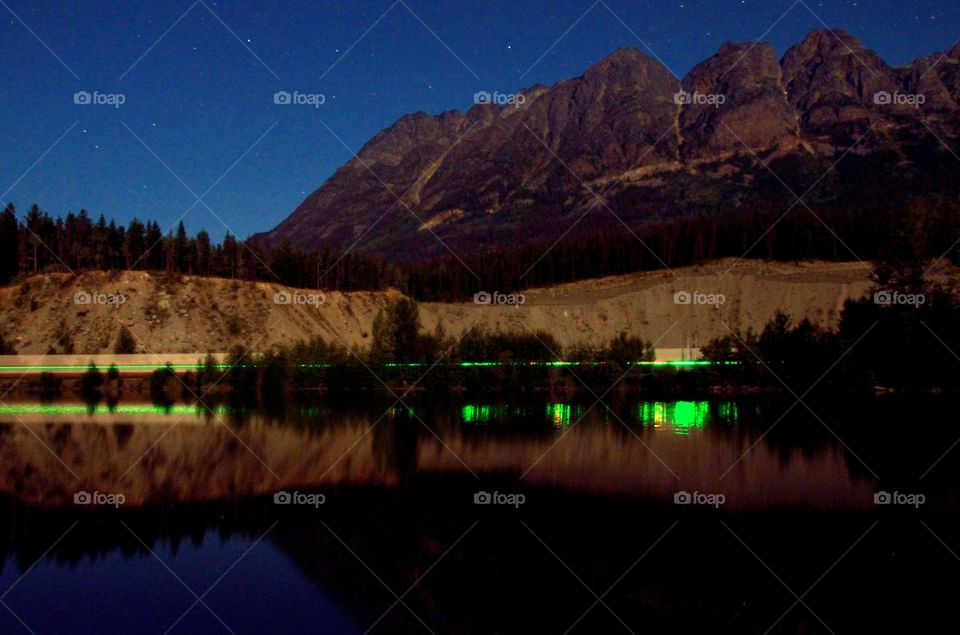 A crystal clear reflection of the mountain, the night sky, and the stars on a still lake.