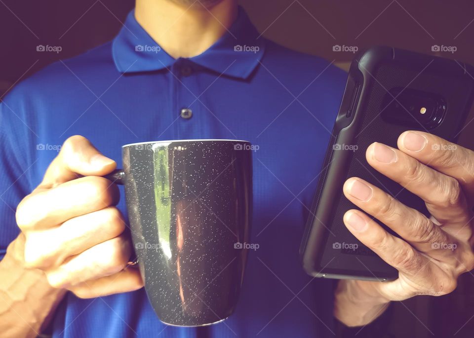 Closeup of a man wearing a polo shirt and drinking coffee while on his cell phone. ( faded Color look )