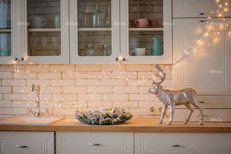 Festive winter cozy kitchen interior with garlands, decorations and gifts.  Christmas dinner at the decorated table.