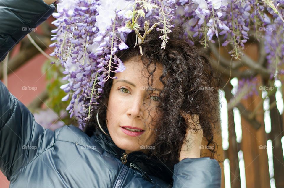 Woman with beautiful curly hair on a background of purple flowers