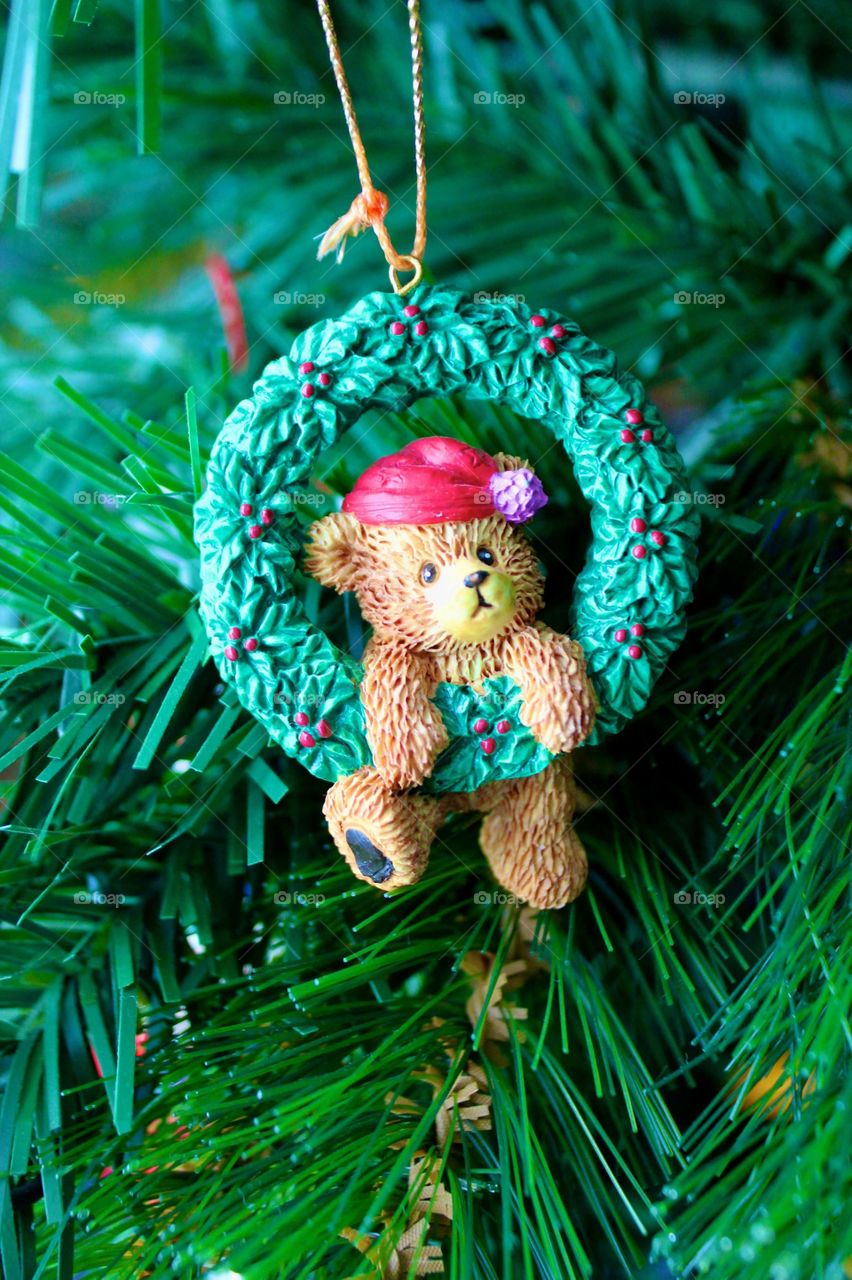 Teddy bear Christmas ornament hanging from a tree.