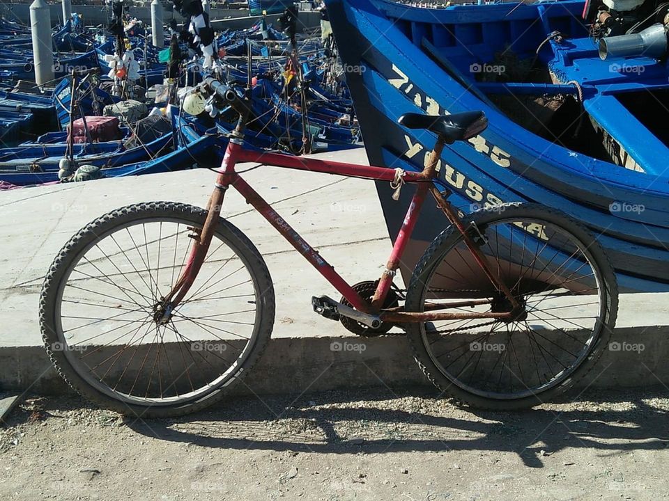 Beautiful bicycle near a blue boat at essaouira harbour in morocco.