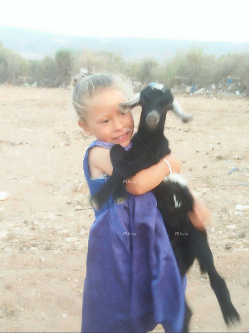 Beautiful girl holding a baby goat.