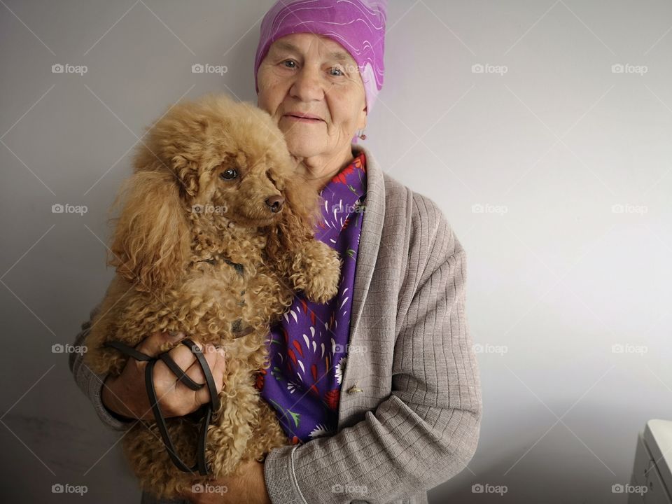 Senior woman hugging poodle dog