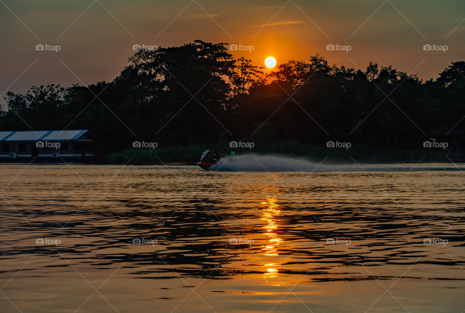 Tourists drive the Jet Ski and the sunset light in Khwae Noi river at Kanchanaburi Thailand .December 2, 2018