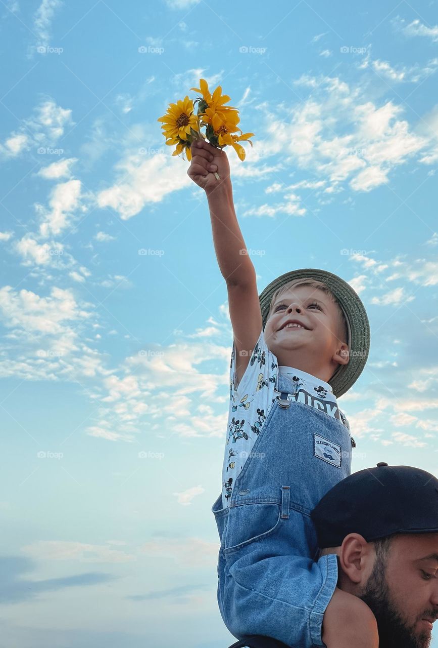 Smiling boy hold summer flowers