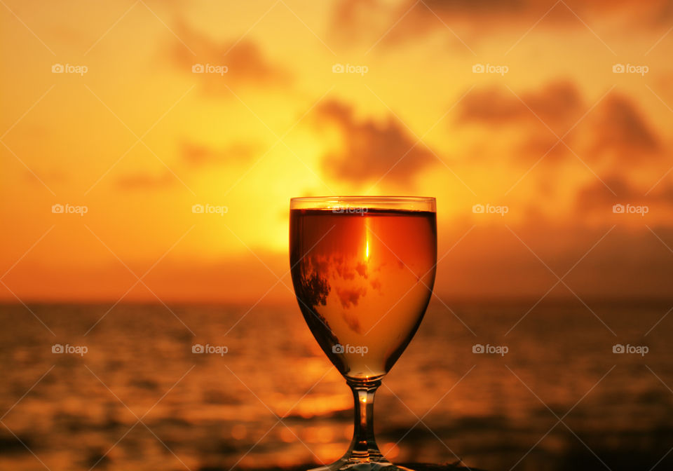 A glass of wine on beach during sunset