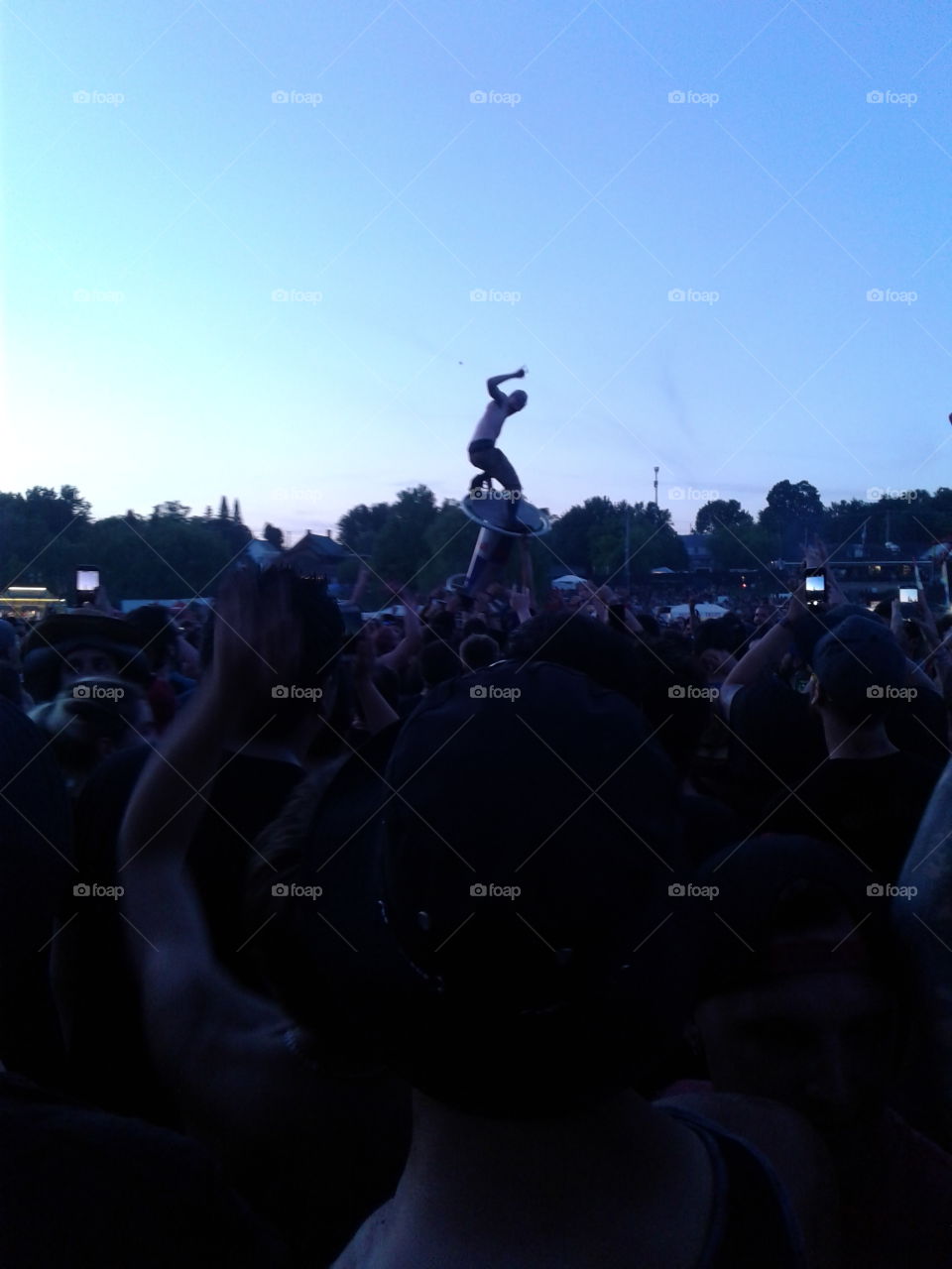man on a table being lifted by the crowd, tabels were near a drink tent.