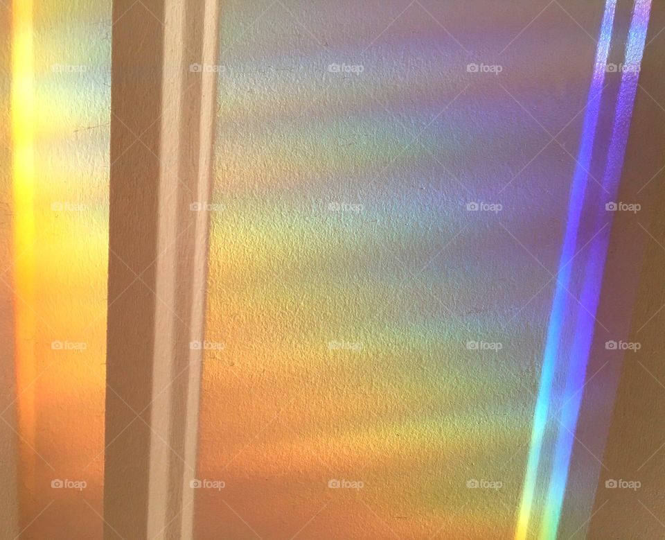 A rainbow of spectral light rays brightly shining on a the wall.