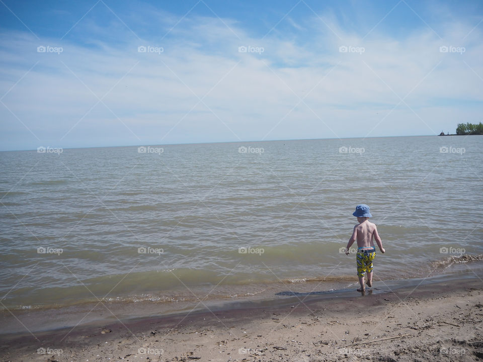 Toddler boy gazing out into the ocean at Port Burwell beach.