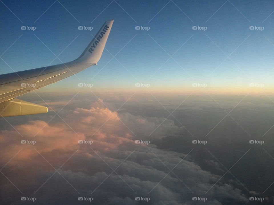 wing aircraft flying in the cloudy sky during sunrise
