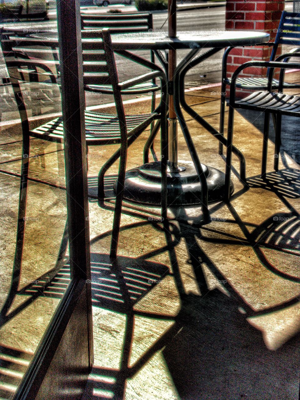 Morning sun hits table and chairs creating a series of defined shade lines while a glass door was closing