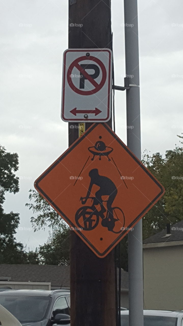It's an orange sign with a cyclist and a UFO on it underneath a No Parking sign on a light pole. If you know what the orange sign means please comment.