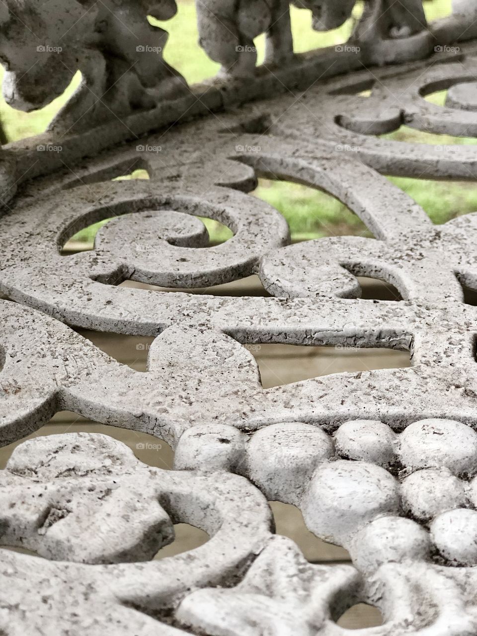 Extreme closeup of wrought iron bench with multiple coats of paint and dirt
