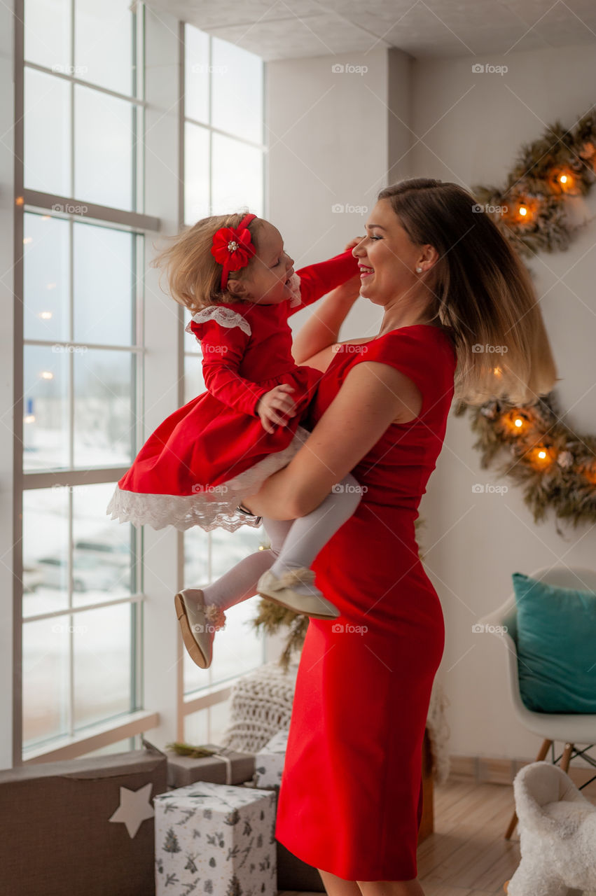 happy mom with a daughter in her arms dance for Christmas near the Christmas tree and gifts