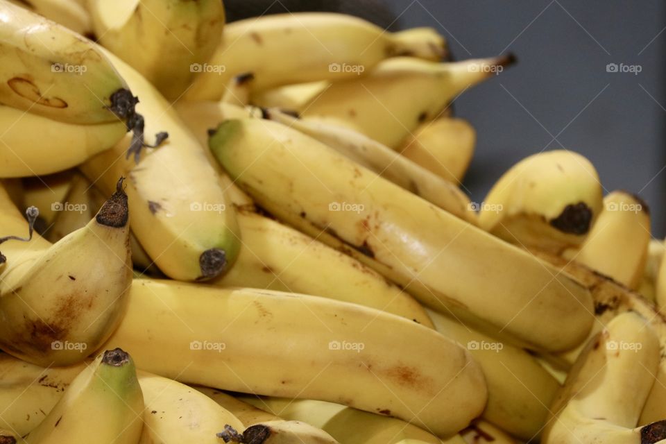 Bunches of ripe yellow organic bananas stacked in pile, copy text space, selective focus, fruit ingredient for desserts, breads, nutritious, delicious and healthy