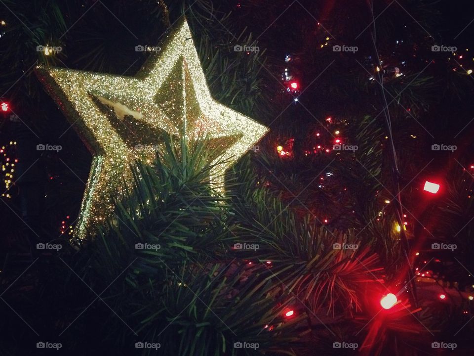 Gold plastic star, balls, red lights garland and other Christmas decorations on artificial fir tree in Moscow, Russia