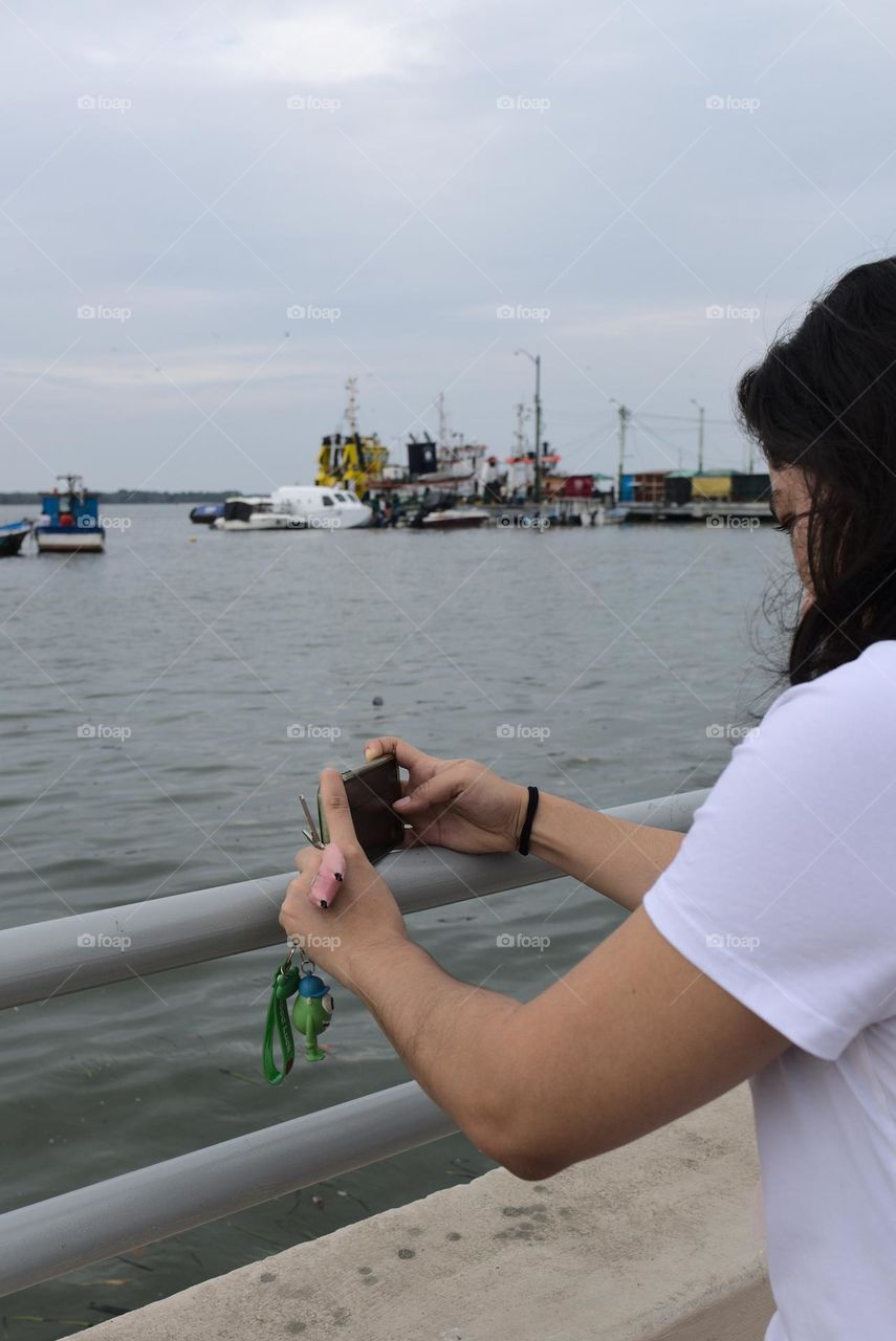 Young woman using cell phone to record a video on the beach