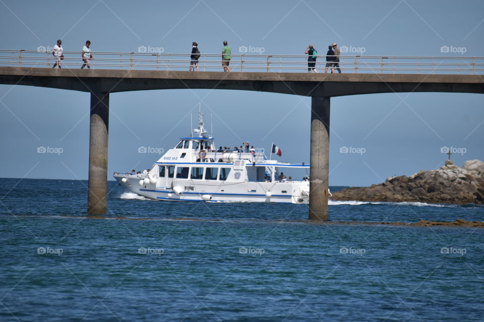 A ship and a bridge in a coastal scenery with sea and horizon