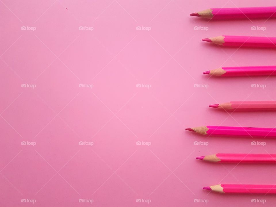 Row of colored pencils on pink background