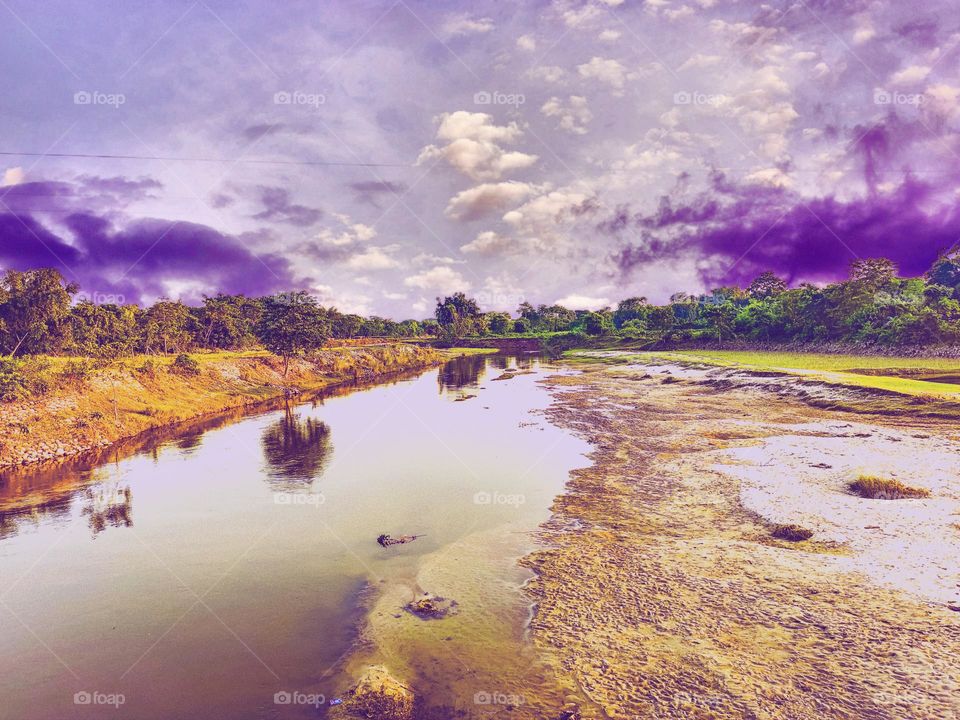 I took this picture of the river.  The picture of the river looks very beautiful.  There are blue clouds above the river.  And there are green trees below.  This scene looks very beautiful.