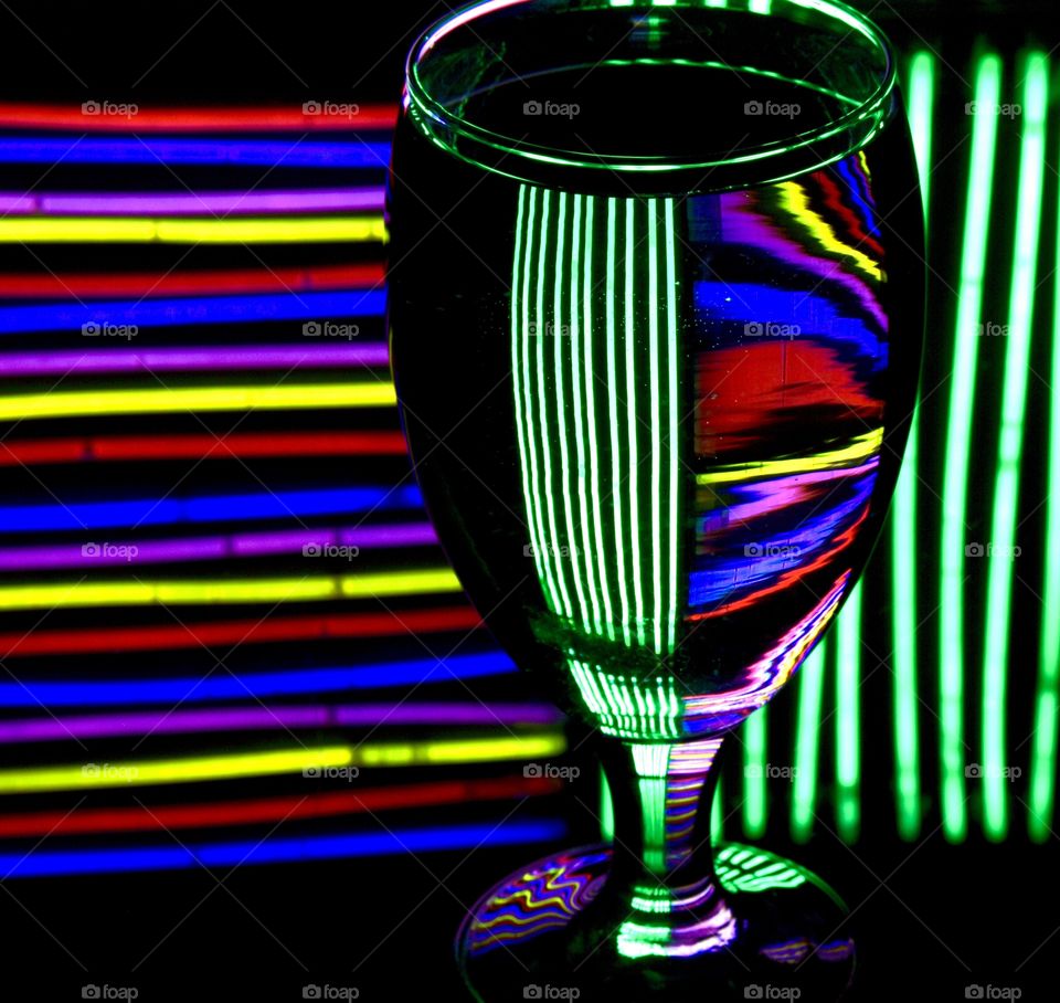 Glow sticks reflected into a wine glass filled with water, bright colors