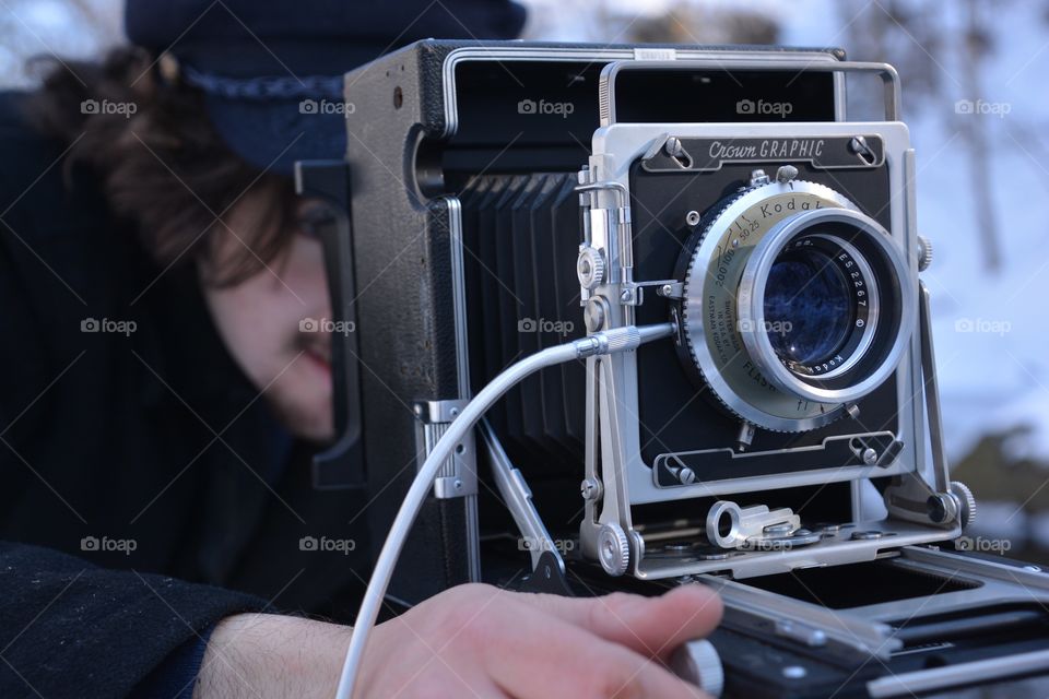 A man uses the old fashion photography equipment of a film camera to capture his image 