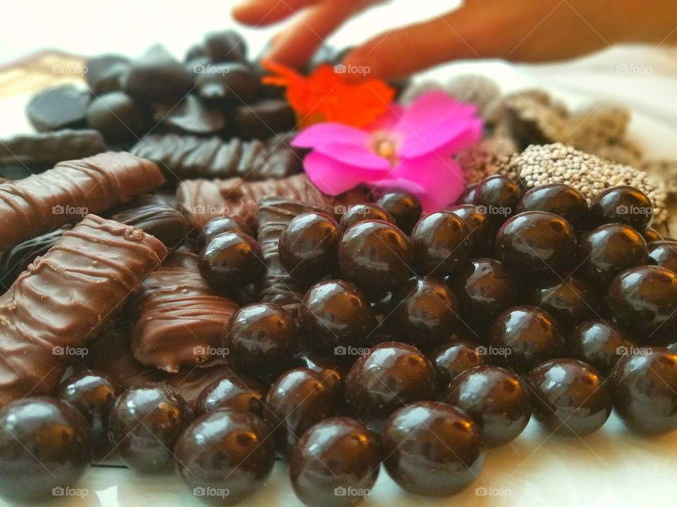 woman's hand selecting from assorted chocolate plate with flowers