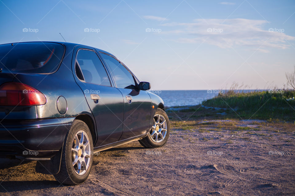 The car stands on the seashore at sunset