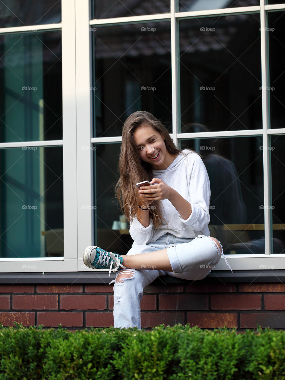 Smiling young girl is using mobile