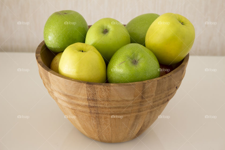 Green yellow apples in wood bowl 