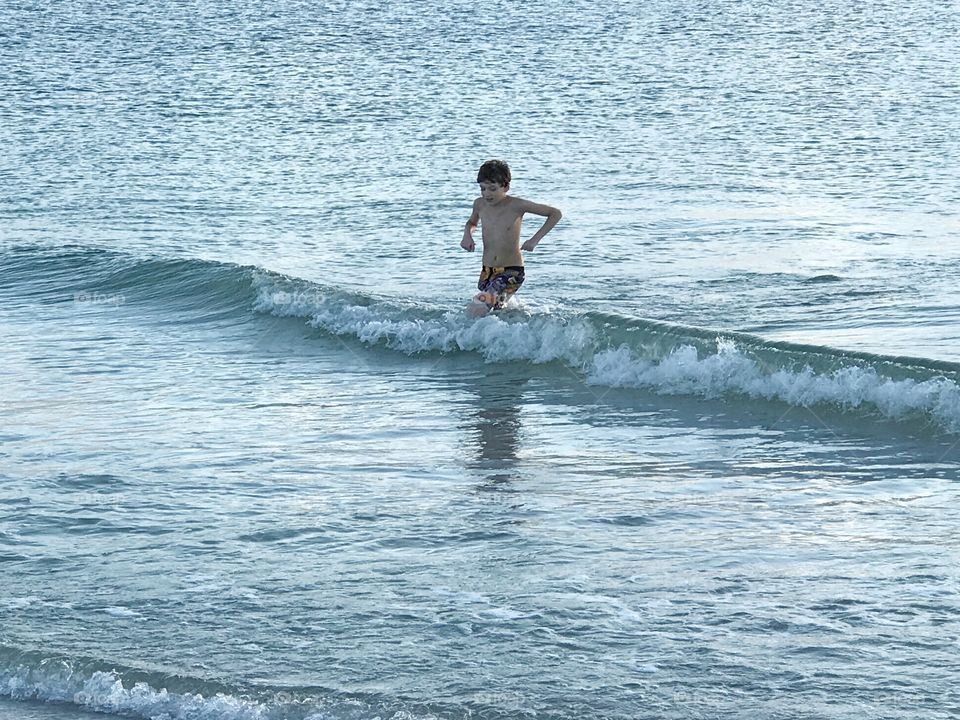 Boy playing in the ocean.